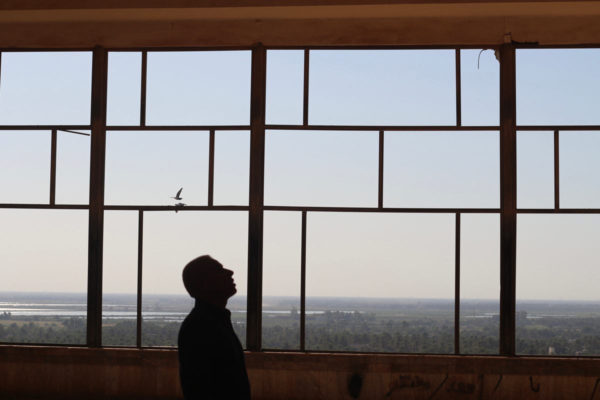  Un hombre se para frente a una ventana en el palacio abandonado de Saddam. Pesha Magid